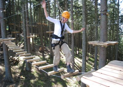 A guest in a ropes course walking over a bridge