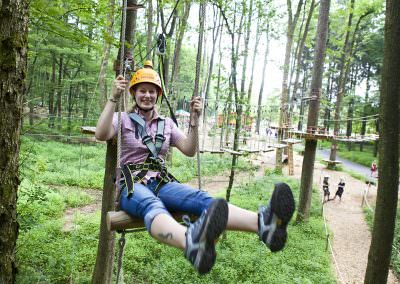 A guest in a ropes course sitting on a giant swing