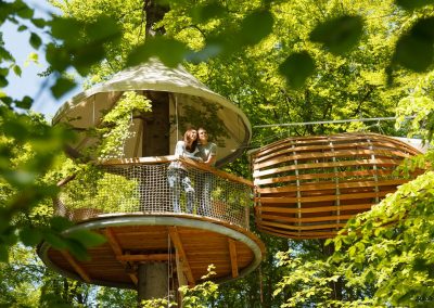 Guests stand in a tree house in the sun