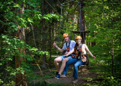 Two guests sitting on a partner swing in a ropes course