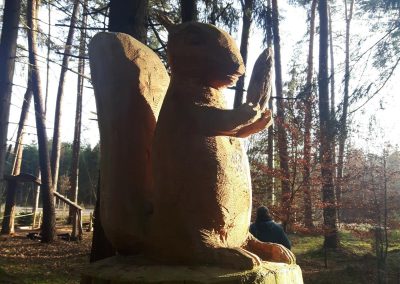 A carved squirrel sits on a tree stump