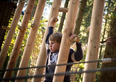 Ein Kind klettert in einem Waldspielplatz