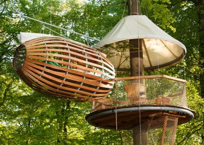 A tree house with sleeping facilities as part of an adventure hangs from a tree