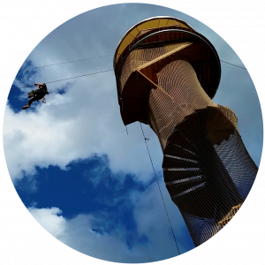 A guest takes off from the platform of a Ziplinetower with a spiral staircase