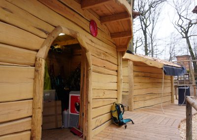 Eingang einer rustikalen Holzhütte aus Robinie in einem Kletterwald