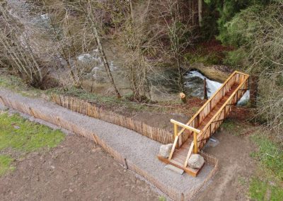 Bird's-eye view of a footbridge over a small ravine as part of a themed trail